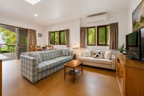 Una sala de estar con sofá, mesa de centro, televisor y un comedor con sillas y mesa.