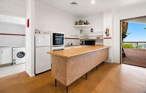 A modern kitchen with a central island, built-in appliances, and a view to an outdoor deck. - Epic Hinterland & Ocean Views - Farm Stay (Mapleton)