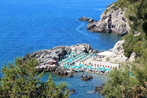 A coastal hotel with a rocky shoreline, a pool area with umbrellas, and a building with a white facade. - Holiday home with a/c (Talamone)