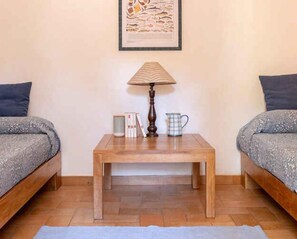 A room with two beds, a wooden table, a lamp, and a framed picture on the wall. - Holiday home with a/c (Talamone)