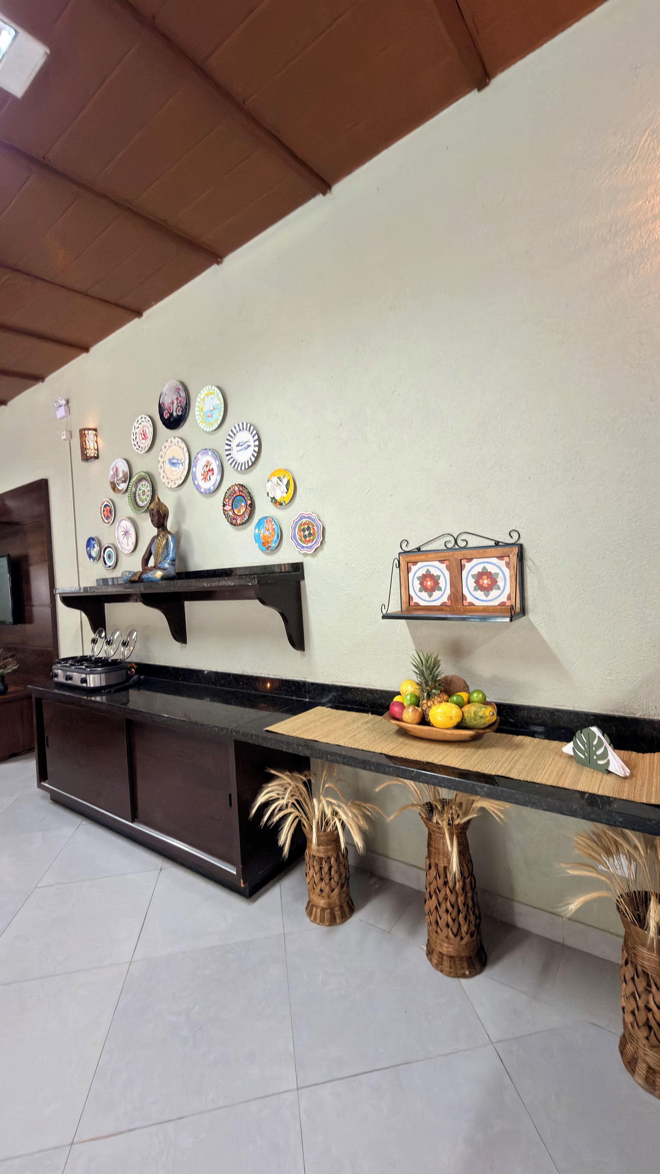 Una cocina con encimera negra, estufa y una pared decorada con platos y una pequeña estatua.