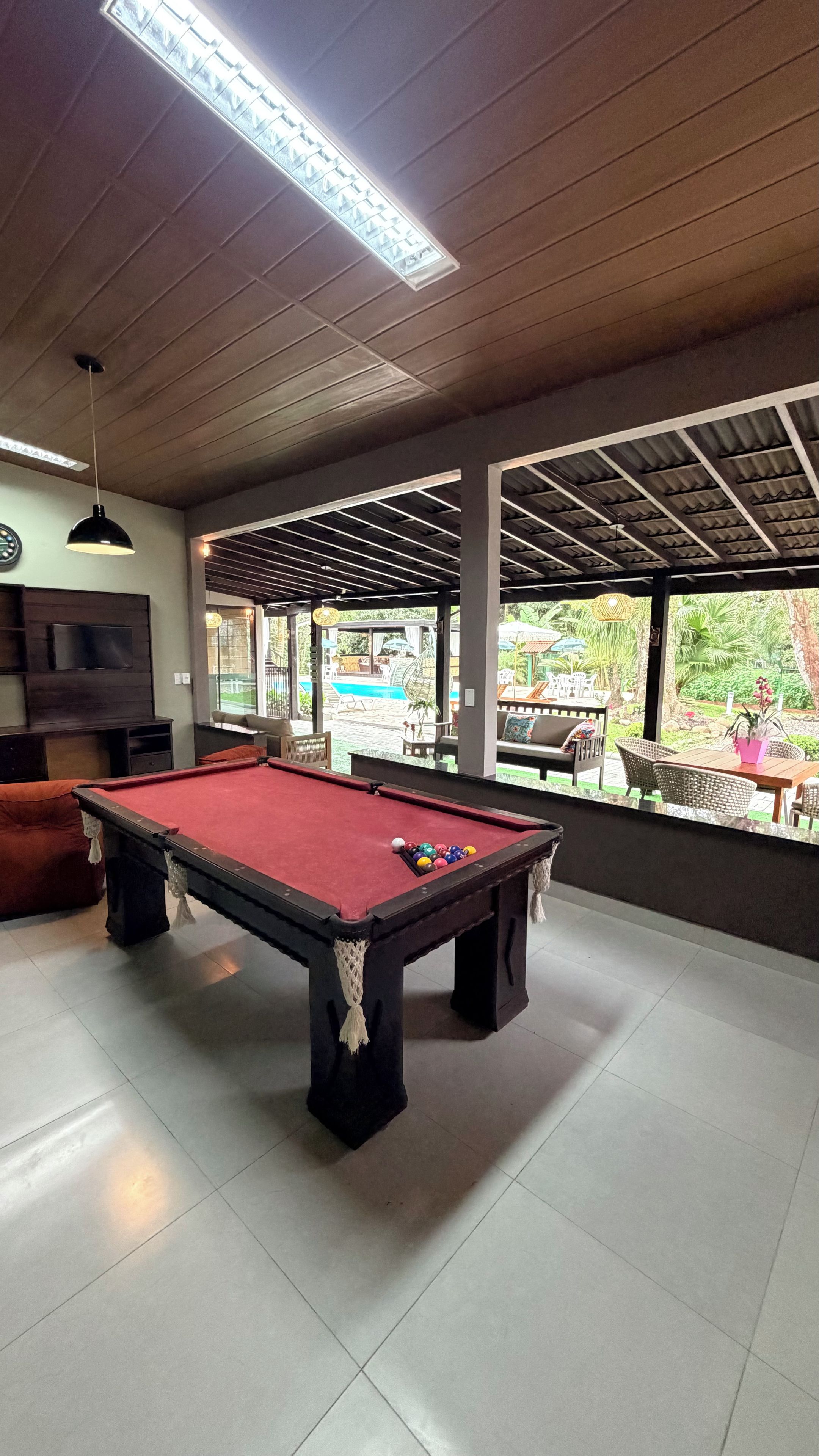 A pool table in a room with a view of a pool outside.