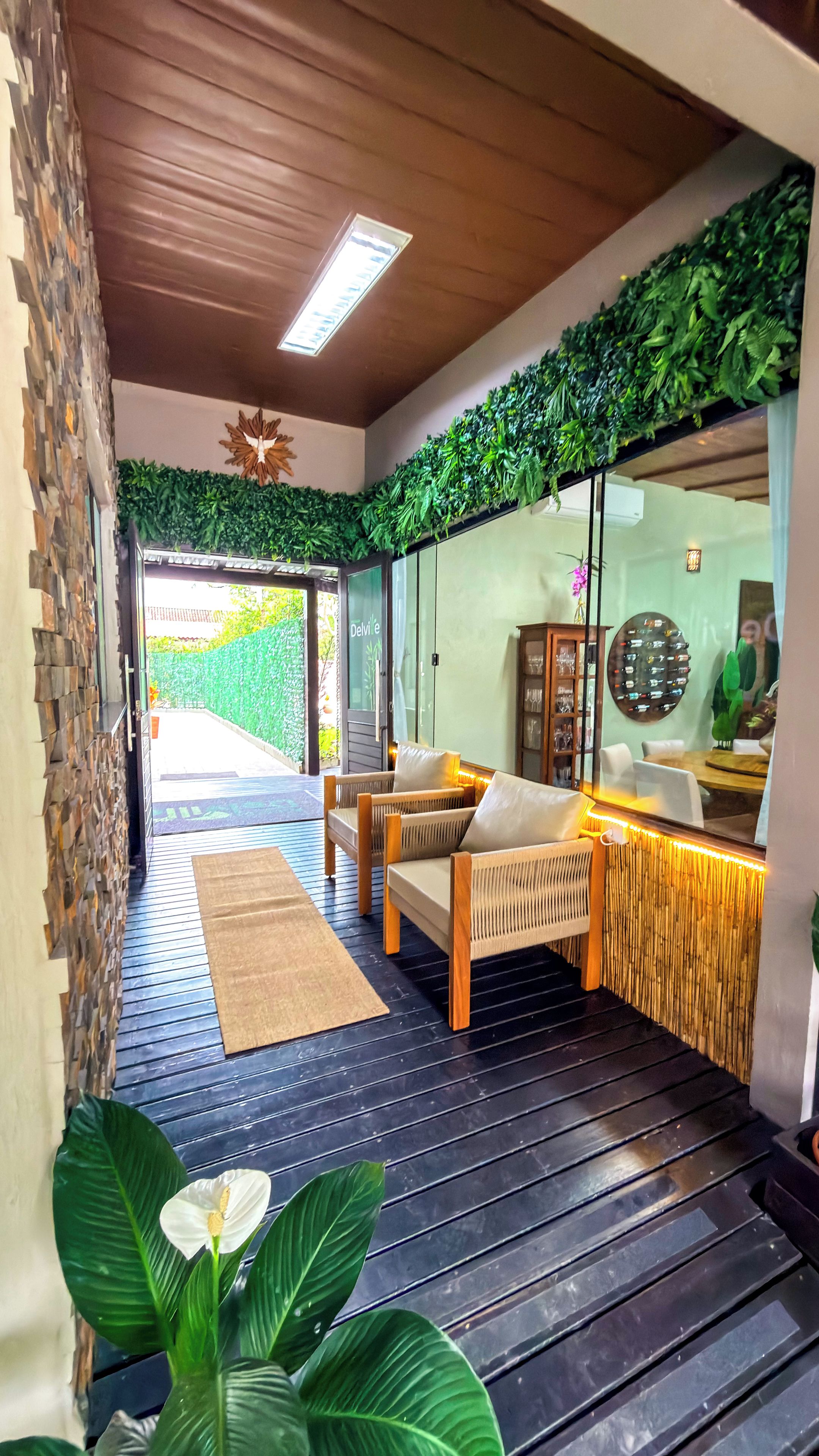 Un intérieur moderne avec un coin salon, une entrée avec une porte vitrée et un plafond en bois.