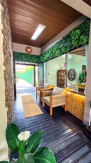 A modern interior with a seating area, a glass door entrance, and a wooden ceiling.