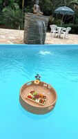 Piscina com cesta flutuante contendo alimentos e bebidas.