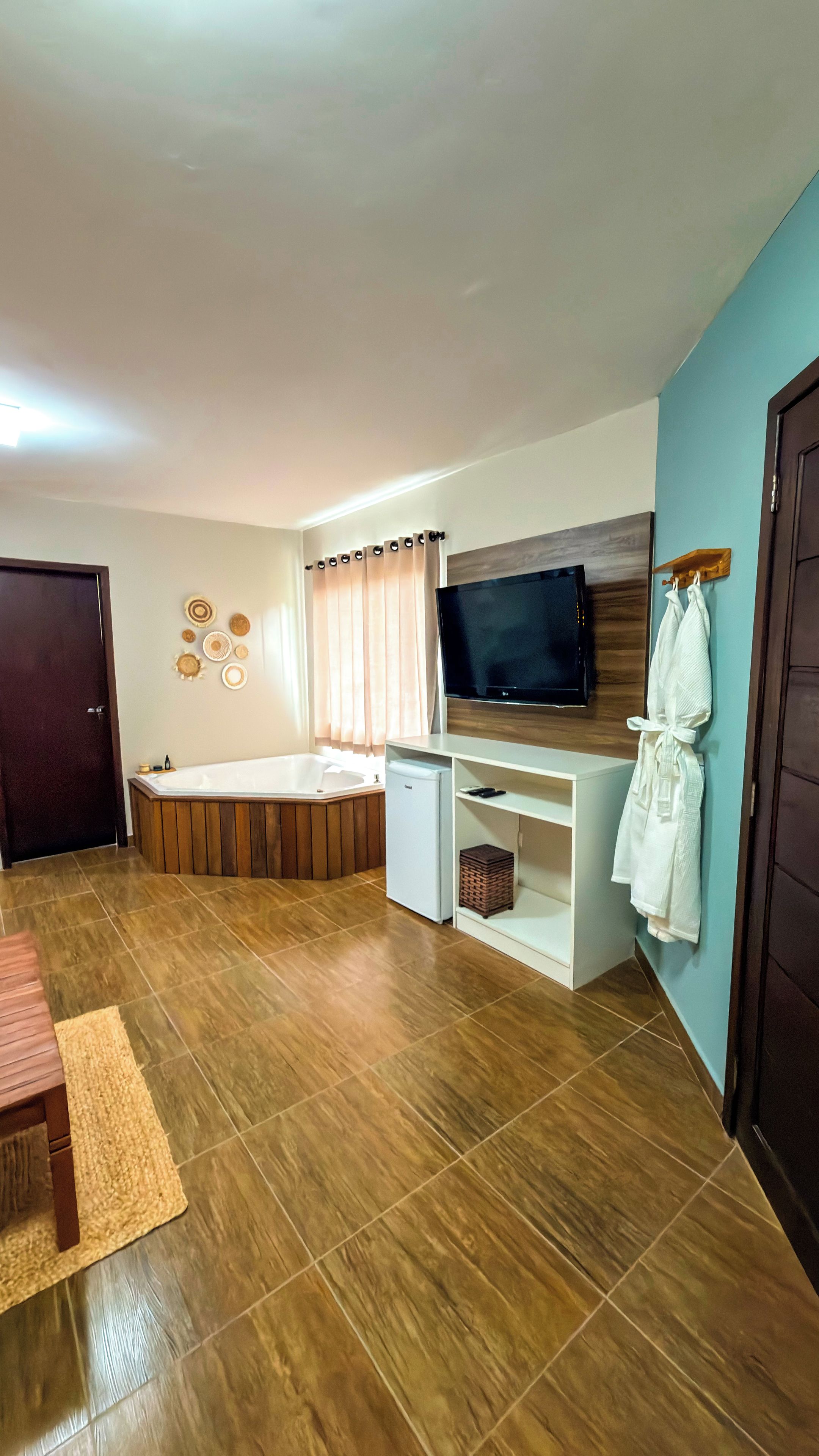Un salon moderne avec un téléviseur à écran plat, une baignoire en bois, un meuble blanc et un mur bleu.