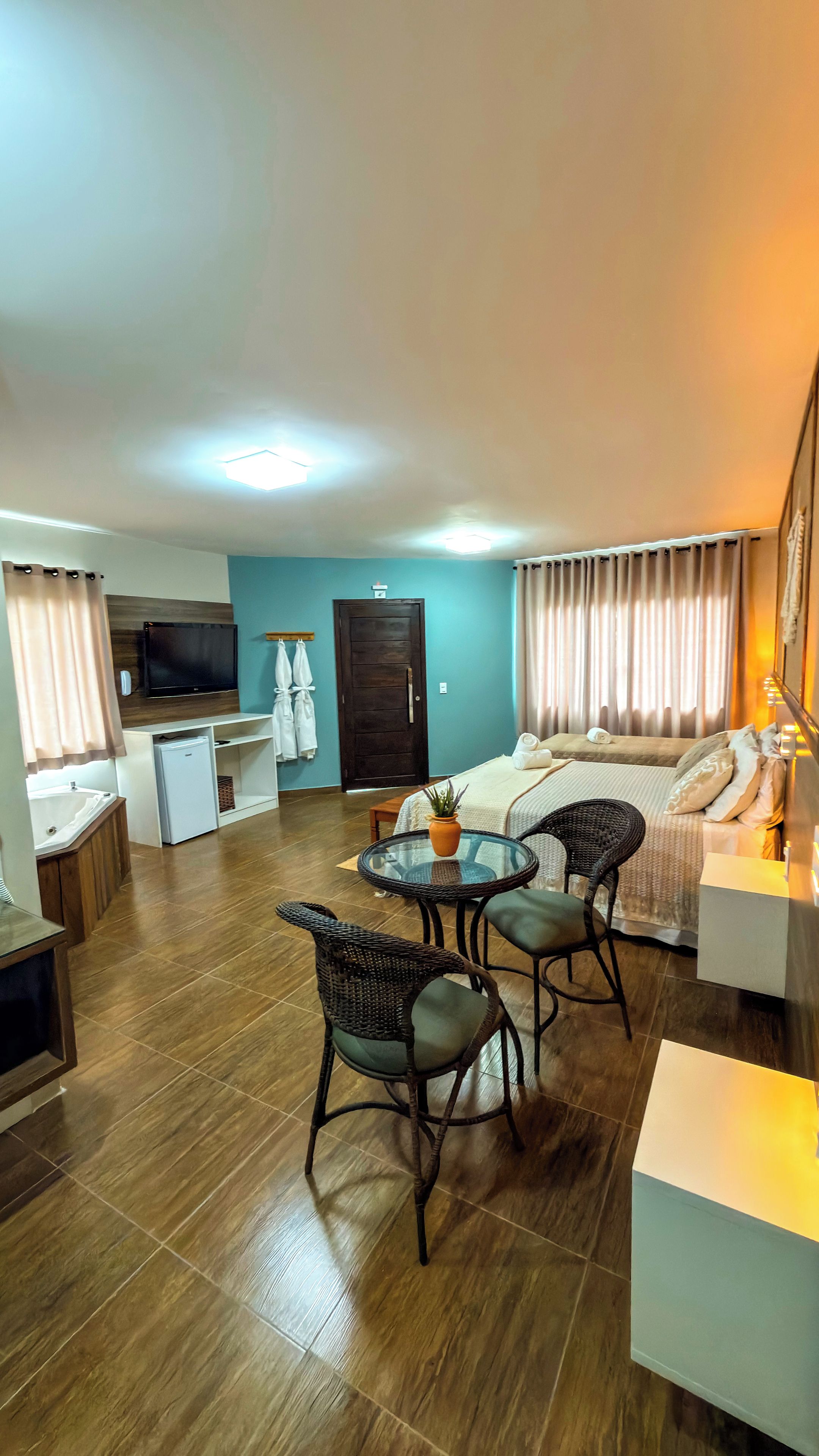 Una sala de estar moderna con un sofá, una mesa de comedor con sillas, una pequeña cocina y un televisor montado en la pared.