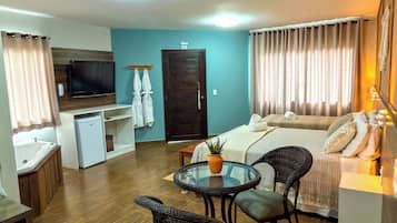 Una sala de estar moderna con un sofá, una mesa de comedor con sillas, una pequeña cocina y un televisor montado en la pared.