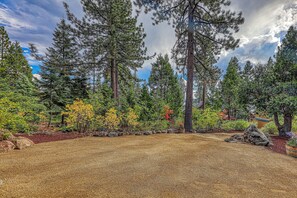 A forested area with a gravel path and a variety of trees, including tall pine trees and smaller deciduous trees. - Topaz Lake View at Dollar Point by Tahoe Getaways - Pet-Friendly 5BR w/ Private Hot Tub (Tahoe City)