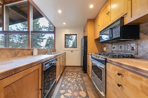 A kitchen with wooden cabinets, a stainless steel refrigerator, a microwave, and a stove. - Topaz Lake View at Dollar Point by Tahoe Getaways - Pet-Friendly 5BR w/ Private Hot Tub (Tahoe City)