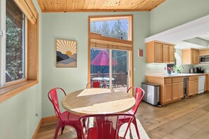 A modern kitchen with wooden cabinets, a stainless steel sink, and a dining area with a wooden table and red chairs. - Monthly Lease - Bright Side at Tahoe Donner by Tahoe Getaways - Pet Friendly 3 BR (Truckee)
