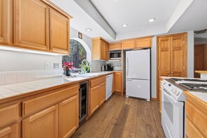 A modern kitchen with wooden cabinets, a stainless steel refrigerator, a microwave, and a dishwasher. - Monthly Lease - Bright Side at Tahoe Donner by Tahoe Getaways - Pet Friendly 3 BR (Truckee)