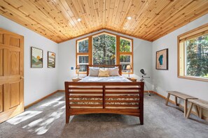 A bedroom with a wooden ceiling, a large bed, multiple windows, and artwork on the walls. - Monthly Lease - Bright Side at Tahoe Donner by Tahoe Getaways - Pet Friendly 3 BR (Truckee)