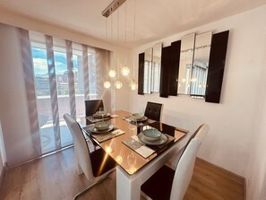 A dining area with a table set for four, modern chairs, and a large window with curtains. - New Listing (Medellín)