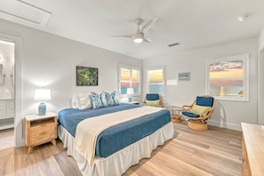 A bedroom with a bed, a chair, a table, and a ceiling fan. - White Heron | Beachfront Gulf Views, Access to Pool, Manasota Key (Englewood)