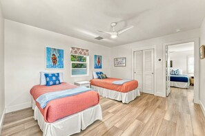 A bedroom with two beds, a ceiling fan, and artwork on the walls. - White Heron | Beachfront Gulf Views, Access to Pool, Manasota Key (Englewood)