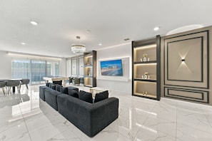 A modern living room with a sectional sofa, a pool table, and a large flat-screen TV. - Sonoma Resort | 15BR Mansion, Pool, Sleeps 30 (Kissimmee)