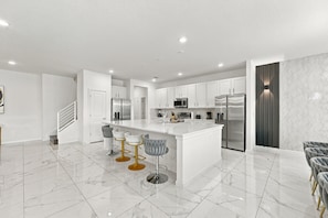 A modern kitchen with white cabinets, stainless steel appliances, and a marble countertop. - Sonoma Resort | 15BR Mansion, Pool, Sleeps 30 (Kissimmee)