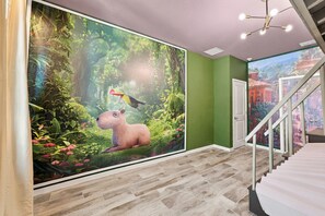 A hallway with a mural of a jungle scene, a staircase, and a door leading to another room. - Sonoma Resort | 15BR Mansion, Pool, Sleeps 30 (Kissimmee)
