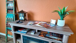 Un escritorio de madera con revistas, una revista de ciclismo, una pequeña planta en maceta y un farol.