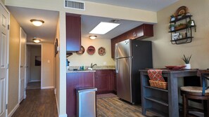 Una cocina compacta con refrigerador, lavamanos y armarios de madera.