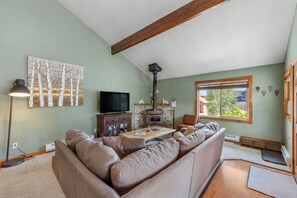 A living room with a sectional sofa, a fireplace, a television, and a large window.