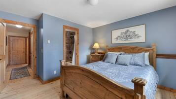 Une chambre à coucher avec un lit en bois, une table de chevet, une lampe fixée au mur et un tableau encadré.
