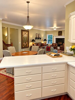 A spacious living room with a large island, a fireplace, and a staircase leading to another level. - South Main Street Cottage - Leland, Michigan - Saturday to Saturday (Leland)