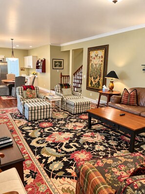 A living room with a large floral rug, striped sofas, a wooden coffee table, and a painting on the wall. - South Main Street Cottage - Leland, Michigan - Saturday to Saturday (Leland)
