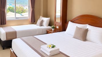 A hotel room with two beds, a large window with curtains, a painting on the wall, and a view of the outside.