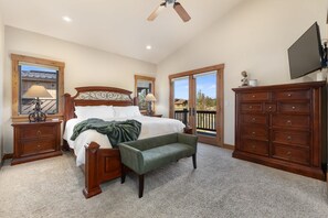 A bedroom with a large bed, a bench, a dresser, and a TV. - Trollhaugen Lodge | 4BR, Sleeps 10, Near Ski Base (Steamboat Springs)