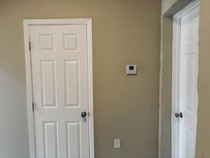 A closed white door with a digital thermostat on the wall. - 2-bedroom apartment cheaper than a hotel, beats the size and price of a hotel. (Presidio)