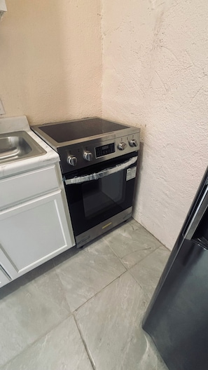 Une cuisine compacte équipée d’un four encastré, d’un évier et d’un réfrigérateur.