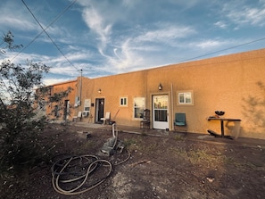 A building with a flat roof, a door, and windows. There are chairs and a table outside. - 2-bedroom apartment cheaper than a hotel, beats the size and price of a hotel. (Presidio)
