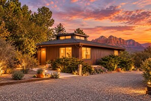A modern house with a large window, surrounded by a gravel driveway and landscaped with various plants. - Welcome to "THE VOC" (Sedona)