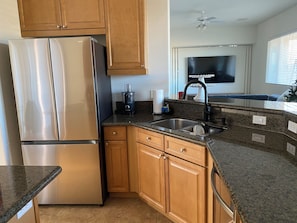 A kitchen with stainless steel appliances, wooden cabinets, granite countertops, and a built-in dishwasher. - Spacious 4-bedroom house in marvelous Desert Hot Springs with AC (Desert Hot Springs)