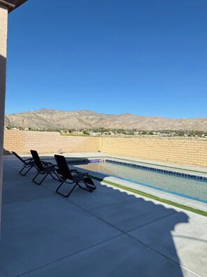 Zona de piscina con sillones de descanso y vistas a las montañas.