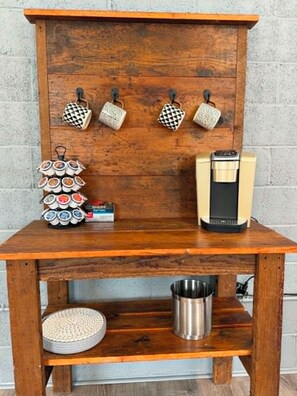 A wooden table with a coffee maker, a mug rack, and a basket of cookies. - Luxurious 1 Bedroom 2nd Story Walk-Up (Wellsville)