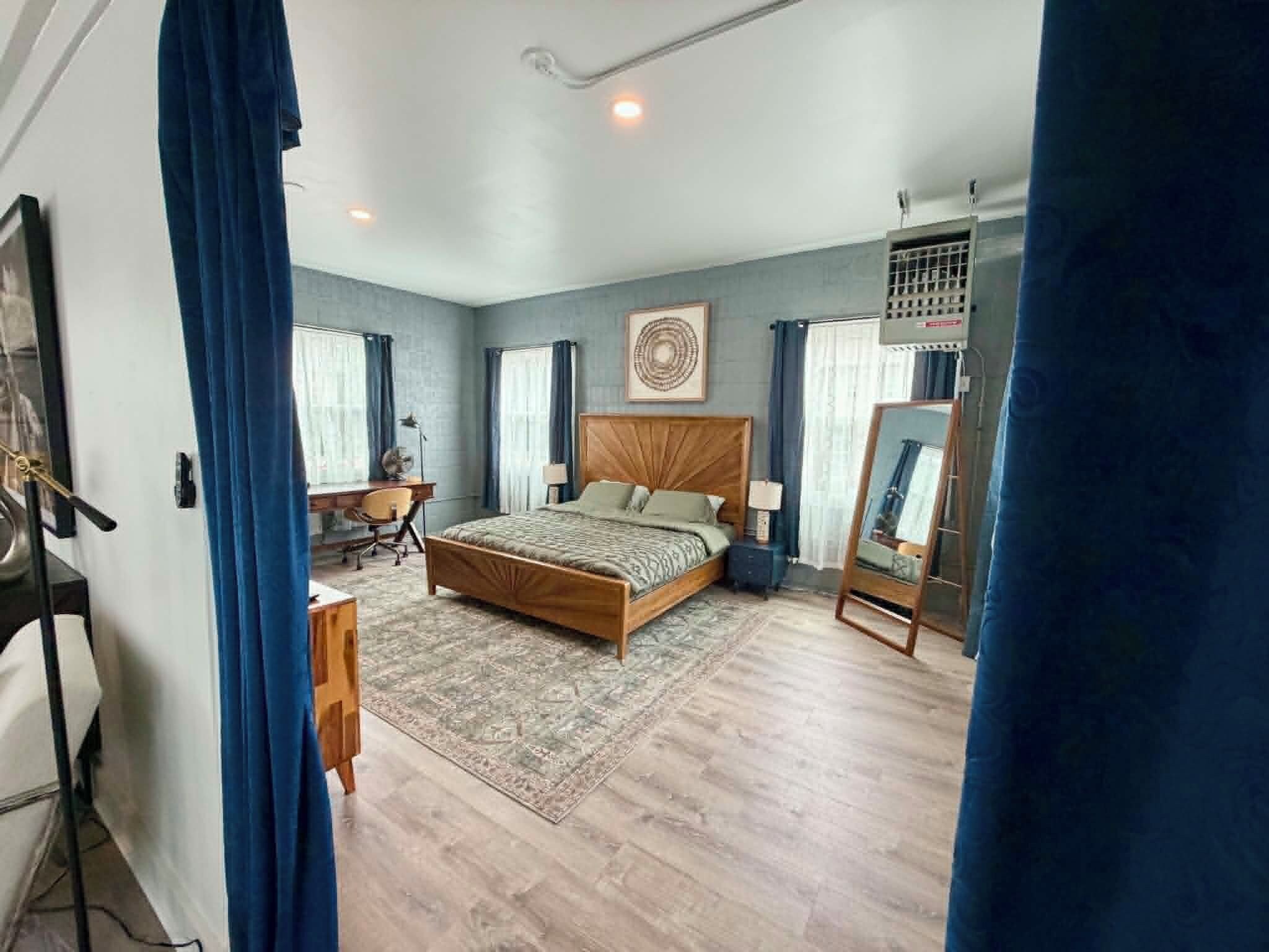 Une chambre à coucher avec un lit, des tables de chevet, un bureau et une chaise.
