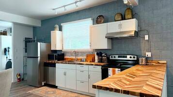 Une cuisine moderne avec des meubles blancs, un plan de travail en bois et une cuisinière intégrée.