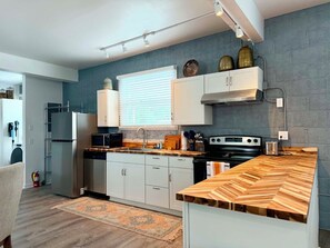 A modern kitchen with white cabinetry, a wooden countertop, and a built-in stove. - Luxurious 1 Bedroom 2nd Story Walk-Up (Wellsville)