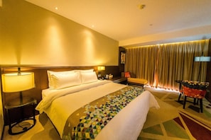 Ein Hotelzimmer mit einem Bett, einem Schreibtisch, einem Stuhl und einer Lampe.