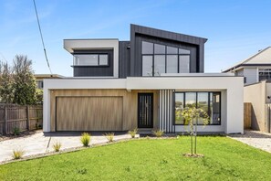 A modern two-story house with a garage, large windows, and a well-maintained lawn. - Indented Head Coastal Retreat | 5BR Escape (Indented Head)