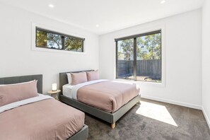 Une chambre avec deux lits, une grande fenêtre et une vue sur l’extérieur.