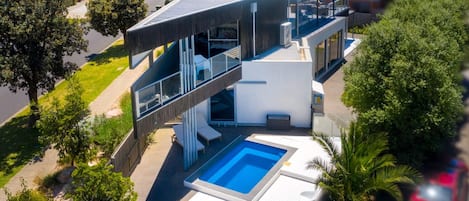 A modern two-story house with a swimming pool, outdoor seating, and a covered patio.