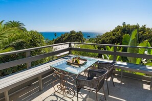 Ein Balkon mit Glastisch und Stühlen mit Blick auf eine schöne Küstenlandschaft.