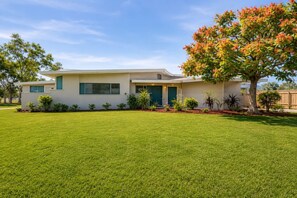 A modern two-story house with a well-maintained lawn and a variety of shrubs and small trees. - Family Tiki Bar, Hot Tub & Grill • 5 min SRQ (Sarasota)