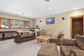 A living room with a pool table, two couches, and a wooden coffee table. - Ski Trail to Door | Hot Tub, Games & Gym (Lincoln)
