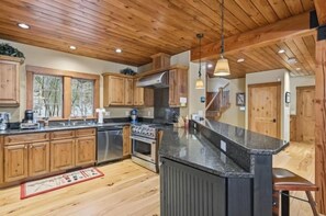 A kitchen with wooden cabinets, a granite countertop, a stove, and a sink. - Ski Trail to Door | Hot Tub, Games & Gym (Lincoln)