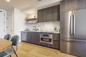 Een moderne keuken met een inbouwoven, een roestvrijstalen koelkast en houten keukenkastjes.